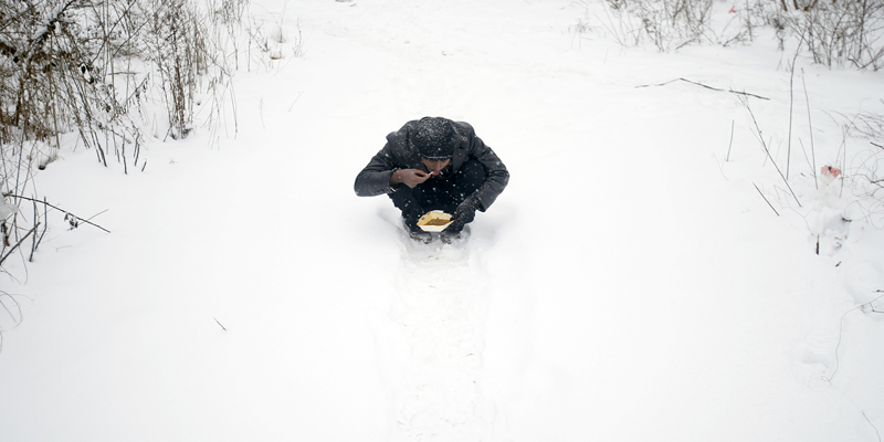 A migrant eats in front of an abandoned warehouse in Belgrade, Serbia, Wednesday, Jan. 11, 2017. Hundreds of migrants are sleeping rough in parks and make-shift shelters in the Serbian capital in freezing temperatures waiting for a chance to move forward toward the European Union. (AP Photo/Darko Vojinovic)