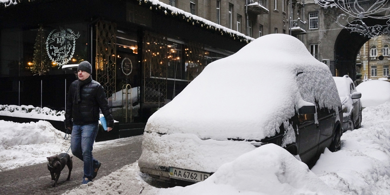 A man walks past some cars covered by snow in Kiev city center, Ukraine, Wednesday, Jan. 11, 2017. The temperature in Kiev is -3 degrees Centigrade (26 degrees Fahrenheit). (AP Photos/Efrem Lukatsky)