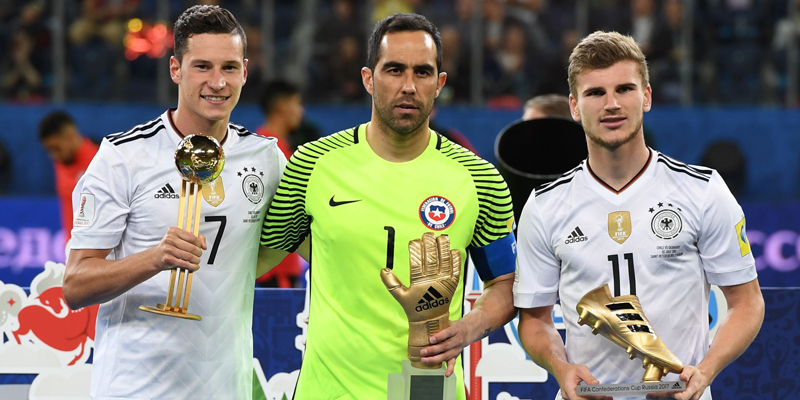 Germany's midfielder Julian Draxler holds the Golden Ball trophy, along side Chile's goalkeeper Claudio Bravo holding the Golden Glove trophy and Germany's forward Timo Werner holding the Golden Boot for best scorer after Germany beat Chile 1-0 in the 2017 Confederations Cup final football match between Chile and Germany at the Saint Petersburg Stadium in Saint Petersburg on July 2, 2017. / AFP PHOTO / Patrik STOLLARZ