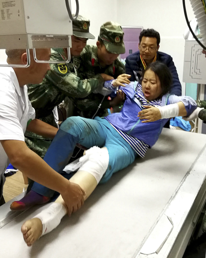 Rescue workers assist an injured woman onto a hospital bed in the aftermath of an earthquake in Jiuzhaigou county in southwestern China's Sichuan province Wednesday Aug. 09, 2017. A strong earthquake shook a mountainous region in southwestern China near a famous national park, killing people and knocking out power and phone networks. (Chinatopix Via AP)
