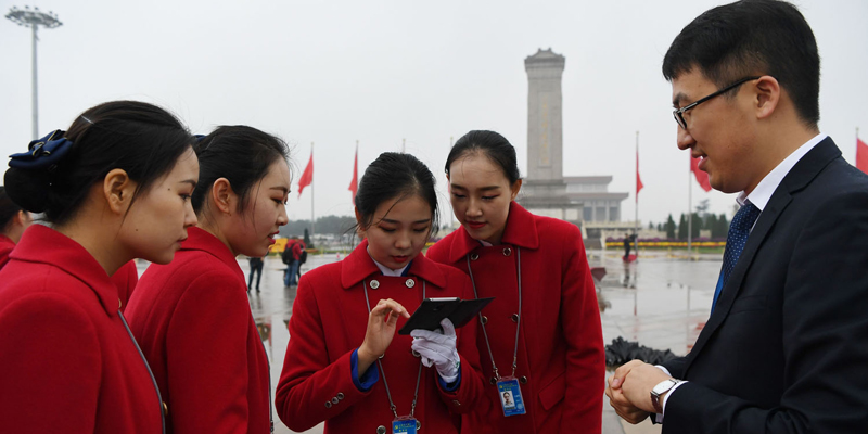Attendants look at photos they took in Tiananmen Square as they wait for delegates during the opening ceremony of the 19th Communist Party Congress in Beijing on October 18, 2017.  The Chinese Communist Party opened its week-long, twice-a-decade congress in the Great Hall of the People on October 18. / AFP PHOTO / GREG BAKER