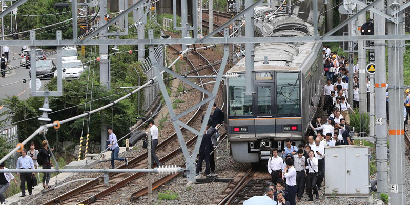 Passengers from a train walk along railroad tracks following an earthquake in Osaka on June 18, 2018. A strong quake hit western Japan early June 18, but there were no immediate reports of major damage or risk of tsunami waves, officials said. / AFP PHOTO / JIJI PRESS / STR / Japan OUT