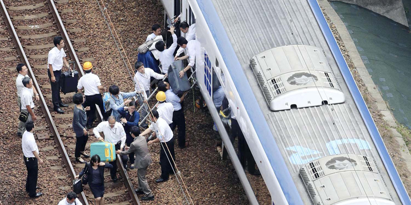 Passengers descend from a train on the track after train service was suspended to check for damage following an earthquake in Takatsuki city, Osaka, western Japan, Monday, June 18, 2018. A strong earthquake knocked over walls and set off scattered fires around metropolitan Osaka on Monday morning. (Kyodo News via AP)