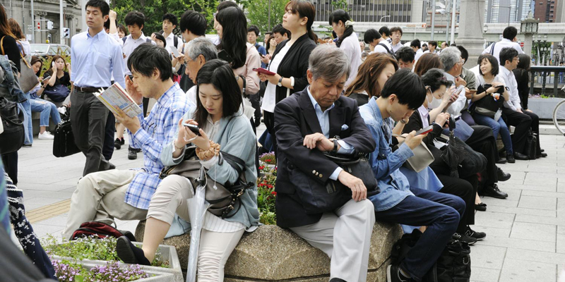 People wait for train service to resume following an earthquake in Osaka, Monday, June 16, 2018. A strong earthquake shook the city of Osaka in western Japan on Monday morning, causing scattered damage including broken glass and partial building collapses. (Junko Ozaki/Kyodo News via AP)