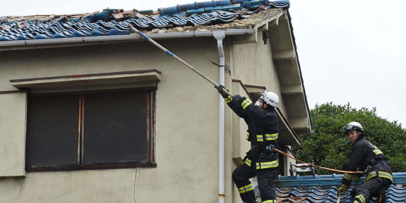Firefighters check a house damaged by an earthquake in Ibaraki City, north of Osaka prefecture on June 18, 2018. A strong quake hit western Japan early June 18, but there were no immediate reports of major damage or risk of tsunami waves, officials said. / AFP PHOTO / JIJI PRESS / STR / Japan OUT