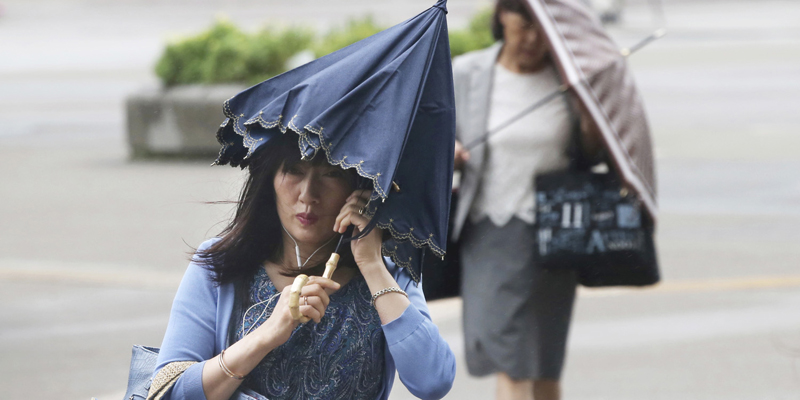 Pedestrians try to hold their umbrellas while struggling with strong winds in Yokohama, near Tokyo, Tuesday, Sept. 4, 2018. Heavy rain and crashing surf were striking western Japan as powerful Typhoon Jebi neared its Pacific coast Tuesday, disrupting train service and air travel. Typhoon Jebi, heading north, was forecast to make landfall later in the day and cross the main island of Honshu. (AP Photo/Koji Sasahara)